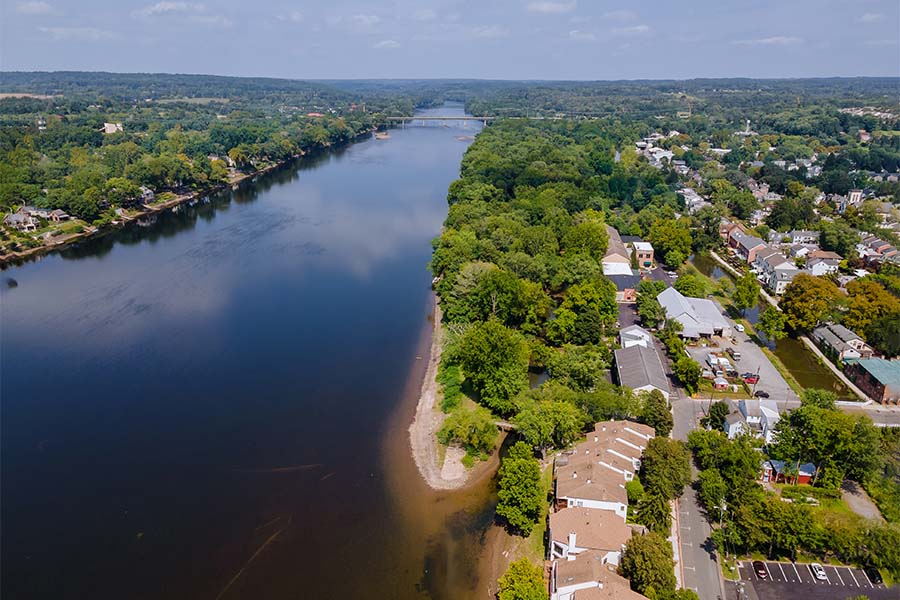 Contact - Scenic View of Homes Next to a River Surrounded by Green Foliage on a Sunny Day in New Jersey