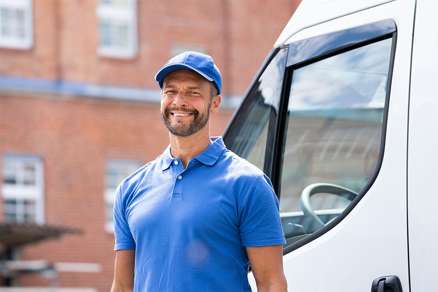 Specialized Business Insurance - Portrait of a Smiling Young Delivery Truck Driver Standing Next to His Van Outside